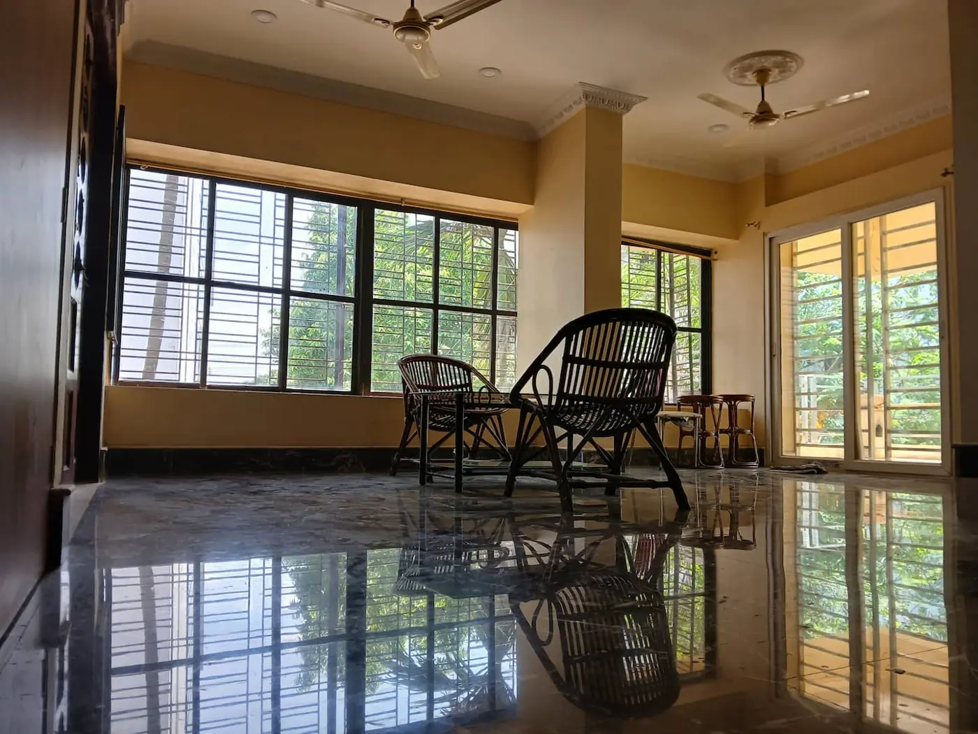 Bright living area with cane chairs and balcony door at Yostel Patia